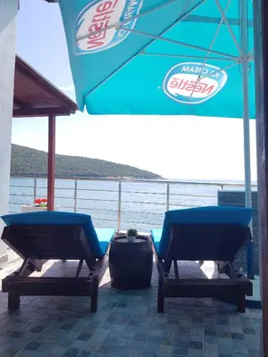 two chairs sitting on a deck with an umbrella at Summer Holiday House MM in Ulcinj