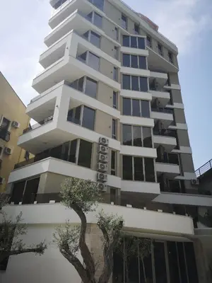 a tall white building with trees in front of it at Lux Apartment Teodora Rafailovici in Rafailovici