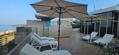 a balcony with white chairs and an umbrella at Lux Apartment Teodora Rafailovici in Rafailovici