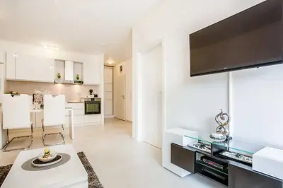 a white living room with a flat screen tv on a wall at Lux Apartment Teodora Rafailovici in Rafailovici