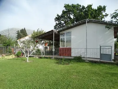 a white house with a red door in a yard at Apartman Zorana in Bar