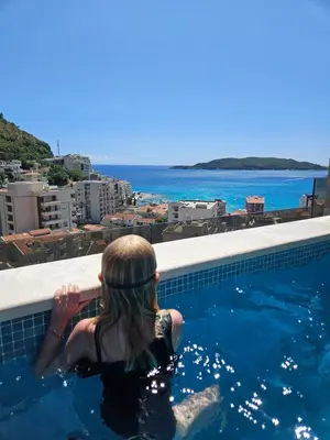 a woman in a swimming pool looking at the ocean at Lunde Sea View Apartment in Rafailovici