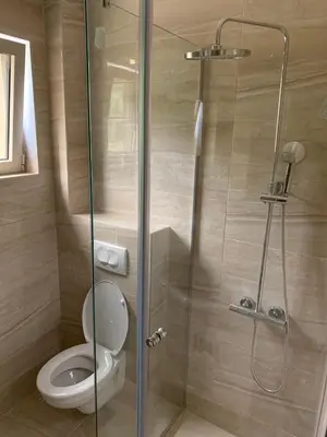 a bathroom with a toilet and a glass shower at Lunde Sea View Apartment in Rafailovici