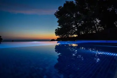 a swimming pool with a sunset in the background at Pino Boutique Hotel in Ulcinj