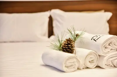 a pile of towels with a pine cone on a bed at Pino Boutique Hotel in Ulcinj