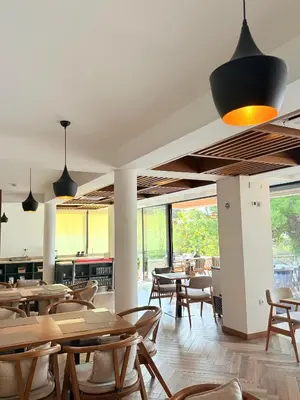 a restaurant with wooden tables and chairs and windows at Pino Boutique Hotel in Ulcinj