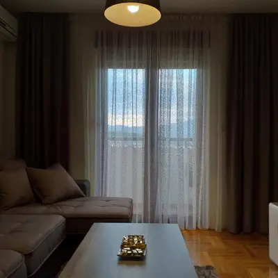 a living room with a couch and a table and a window at Aphrodite Apartment in Podgorica