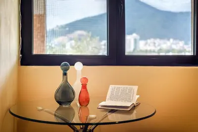 a glass table with three glass vases on it with a window at Villa Milana Budva in Budva