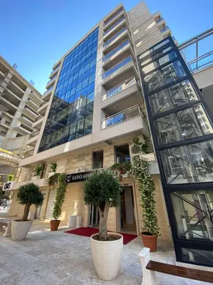a large building with trees in front of it at Gufo Apart in Budva