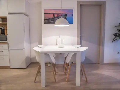 a white dining room with a white table and chairs at Gufo Apart in Budva