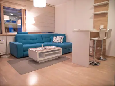a living room with a blue couch and a table at Gufo Apart in Budva
