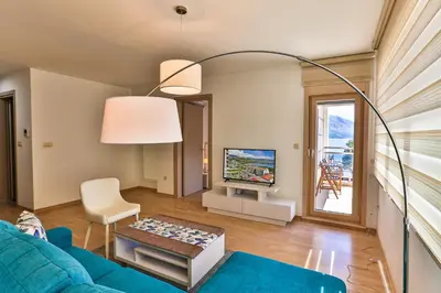 a living room with a blue couch and a tv at Gufo Apart in Budva