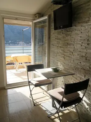 a dining room with a table and chairs and a television at Palma Apartments in Kotor