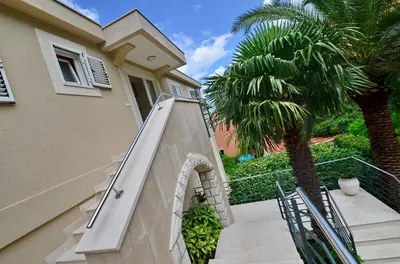 a house with a staircase and a palm tree at Palma Apartments in Kotor