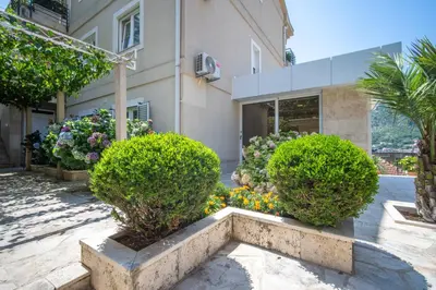 a building with bushes and flowers in front of it at Palma Apartments in Kotor