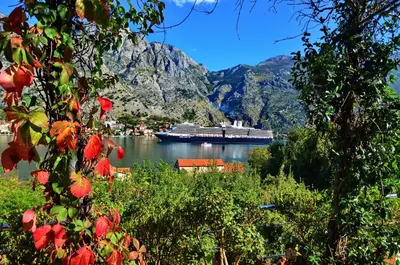a cruise ship in a body of water with mountains at Muo Apartments in Kotor