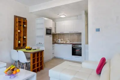 a kitchen with white cabinets and a table in a room at Harmonia Panorama Apartments in Budva