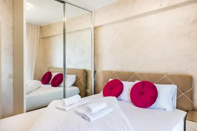 a bedroom with two beds with red pillows and a mirror at Harmonia Panorama Apartments in Budva