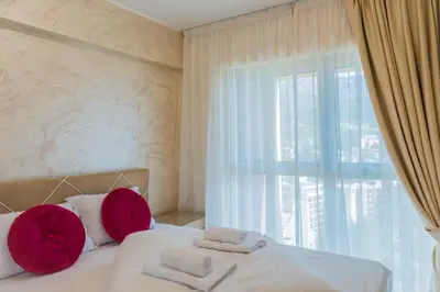 a bedroom with a bed with red pillows and a window at Harmonia Panorama Apartments in Budva
