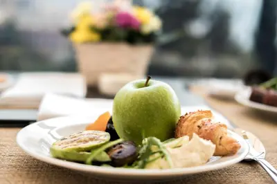 a plate with an apple and vegetables on a table at Harmonia Panorama Apartments in Budva