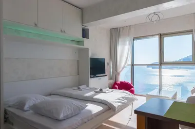 a bedroom with a large bed with a view of the ocean at Harmonia Panorama Apartments in Budva