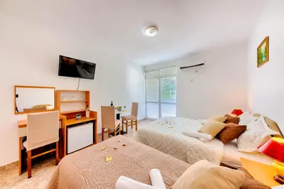 a bedroom with two beds and a desk with a computer at HOTEL DANA in Čanj