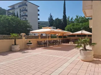 a patio with umbrellas and tables and chairs at HOTEL DANA in Čanj