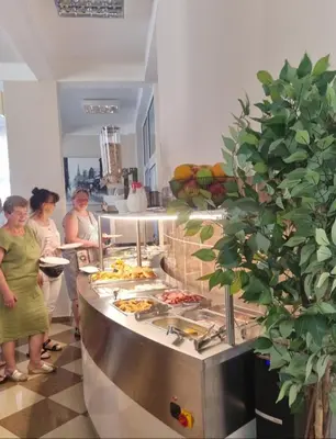 a group of people standing in a kitchen with food at HOTEL DANA in Čanj