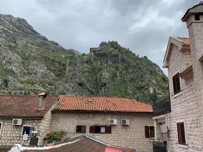 a stone building with a mountain in the background at Viktor Rooms in Kotor
