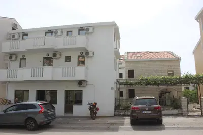 two cars parked in front of a white building at Nir Apartments Budva in Budva