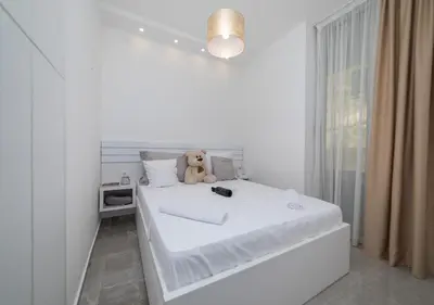 a white bedroom with a teddy bear sitting on a bed at Twins in Rafailovici