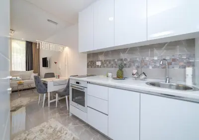 a kitchen with white cabinets and a living room at Twins in Rafailovici