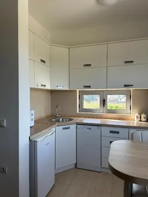 a kitchen with white cabinets and a sink and a table at Premium Lea Apartments in Ulcinj