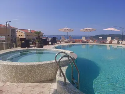 a large swimming pool with chairs and umbrellas at Luxury Villas Marko in Tivat