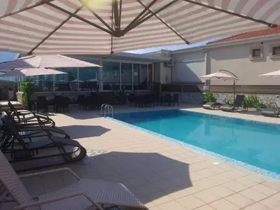 a swimming pool with chairs and umbrellas next to a building at Luxury Villas Marko in Tivat