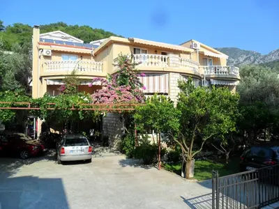 a large building with a car parked in a parking lot at Apartments Kalluka in Sveti Stefan