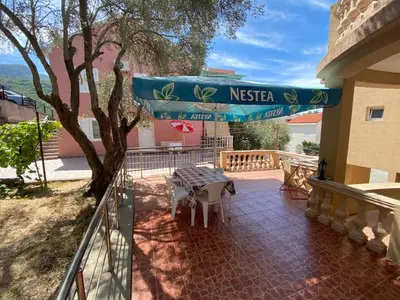 a balcony of a house with a table at Apartments Kalluka in Sveti Stefan