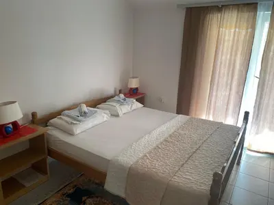 a bedroom with a large bed with white sheets and a window at Apartments Kalluka in Sveti Stefan