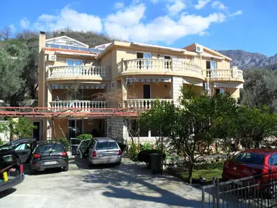 a large building with cars parked in a parking lot at Apartments Kalluka in Sveti Stefan
