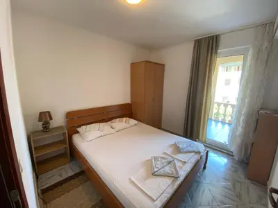 a small bedroom with a bed and a window at Apartments Kalluka in Sveti Stefan