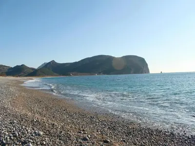 a rocky beach with a mountain in the background at Apartments Galija in Petrovac na Moru
