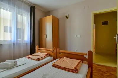 two twin beds in a room with a window at Apartments Srzentic in Petrovac na Moru