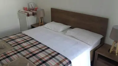 a bedroom with a large white bed and a refrigerator at Apartments Stevo Nikočević in Bar