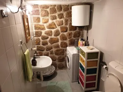 a bathroom with a sink and a stone wall at Lake View Apartment Dodosi in Dodoši