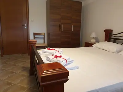 a bedroom with a bed with white sheets and a red ribbon at Lake View Apartment Dodosi in Dodoši