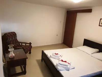 a bedroom with a bed and a table and a chair at Lake View Apartment Dodosi in Dodoši
