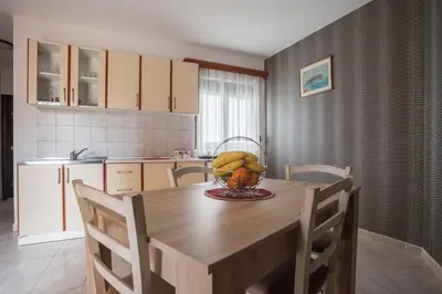 a kitchen with a table with a bowl of bananas on it at Mali Miločer Bay Accommodation in Sveti Stefan