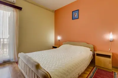 a bedroom with orange walls and a bed and a window at Mali Miločer Bay Accommodation in Sveti Stefan