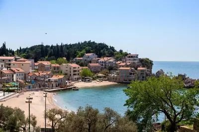 a view of a beach with buildings and the ocean at Mali Miločer Bay Accommodation in Sveti Stefan