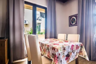 a dining room table with chairs and a floral table cloth at Mali Miločer Bay Accommodation in Sveti Stefan